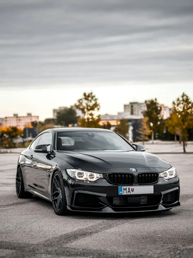 Black sedan standing on an open lot with the skyline behind.