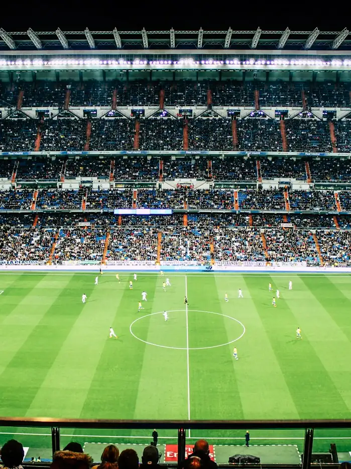 Floodlit pitch and packed stands seen from the upper tier.