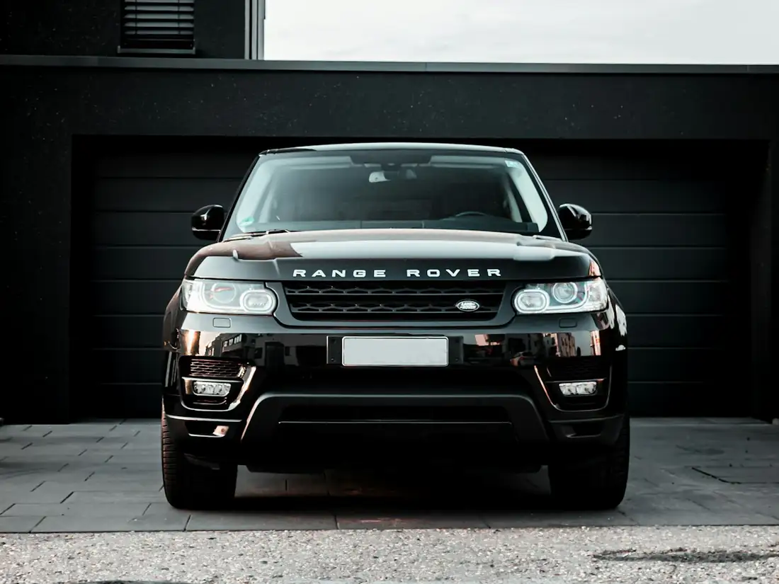 Black full-size luxury SUV parked in a lit garage bay.
